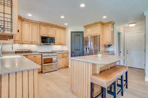Kitchen featuring stainless steel appliances, light brown cabinets, light wood-type flooring, and recessed lighting