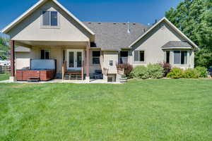 Back of house with a hot tub, french doors, a shingled roof, and stucco siding