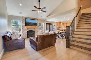 Living room with stairs, light wood-style flooring, a fireplace, a ceiling fan, and recessed lighting