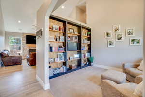 Living area with a stone fireplace, recessed lighting, and light wood-style flooring