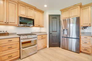 Kitchen with stainless steel appliances, light wood-style flooring, light brown cabinetry, and recessed lighting
