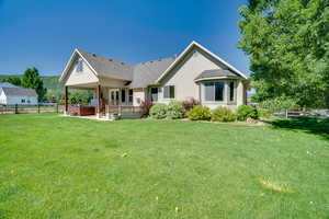 Back of property with stucco siding, a wooden deck, a shingled roof, and a patio area