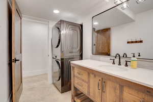 Bathroom featuring stacked washer / drying machine, recessed lighting, vanity, concrete flooring, and a textured ceiling