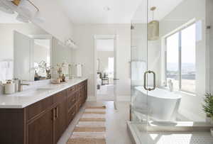 Bathroom with a freestanding tub, double vanity, plenty of natural light, and a shower stall