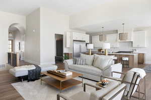 Living area featuring arched walkways, light wood finished floors, a high ceiling, and recessed lighting