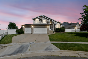 View of front facade featuring driveway, an attached garage, and stucco siding