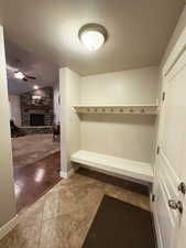 Mudroom featuring a stone fireplace, ceiling fan, vaulted ceiling, and tile patterned floors