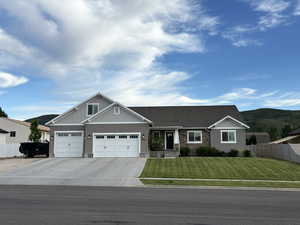 Craftsman house featuring an attached garage, concrete driveway, stone siding, and a mountain view