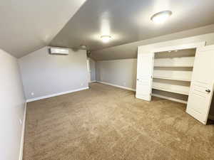 Bonus room with a wall mounted air conditioner, carpet flooring, and lofted ceiling