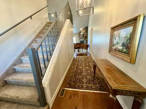 Stairway featuring wood finished floors, a towering ceiling, a fireplace, and a chandelier