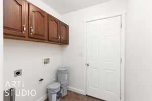 Washroom with electric dryer hookup, dark tile patterned floors, washer hookup, and cabinet space