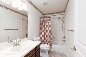 Bathroom featuring shower / bath combo with shower curtain, light tile patterned flooring, vanity, and a textured ceiling