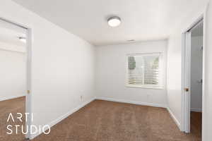Unfurnished bedroom featuring carpet flooring and baseboards and walk-in closet