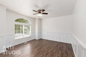 Office with a decorative wall, a wainscoted wall, dark wood-type flooring, and ceiling fan