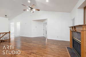 Unfurnished living room featuring dark wood finished floors, a tile fireplace, high vaulted ceiling, and a ceiling fan