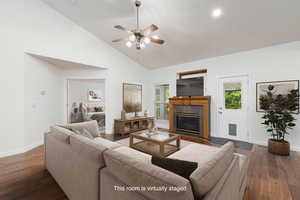 Virtually Staged - Living area with a tiled fireplace, dark wood-style floors, healthy amount of natural light, high vaulted ceiling, and ceiling fan