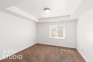 Carpeted bedroom with a raised ceiling and baseboards