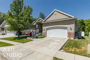Ranch-style house featuring a front lawn, brick siding, a garage, driveway, and stucco siding