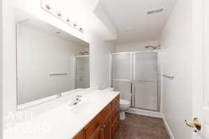 Full bath featuring vanity, a shower stall, and dark tile patterned flooring