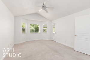 Primary bedroom featuring light colored carpet, vaulted ceiling, and ceiling fan with door to covered deck