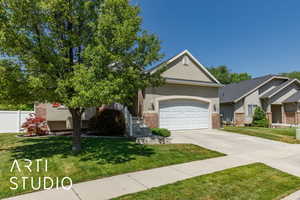 View of front of house with brick siding, driveway, a garage, and stucco siding