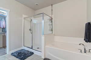 Full bath with a shower stall, a bath, and tile patterned flooring