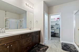Bathroom with a stall shower, double vanity, and a spacious closet
