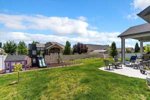 Fenced backyard with a patio, a playground, and an outbuilding