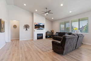 Living room featuring a ceiling fan, light wood-style flooring, high vaulted ceiling, a tile fireplace, and recessed lighting
