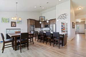 Dining room with high vaulted ceiling, a chandelier, light wood-style floors, healthy amount of natural light, and recessed lighting