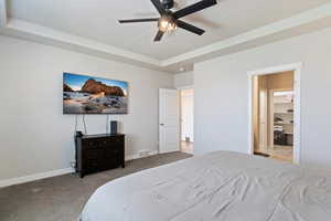 Bedroom with carpet flooring, a tray ceiling, and a ceiling fan