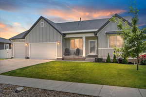 Modern inspired farmhouse featuring board and batten siding, a standing seam roof, concrete driveway, and a garage