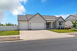 View of front of property featuring board and batten siding, a garage, concrete driveway, roof with shingles, and a porch