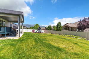 Fenced backyard featuring a playground and a mountain view