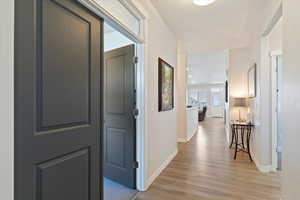 Hall with light wood-style flooring and baseboards