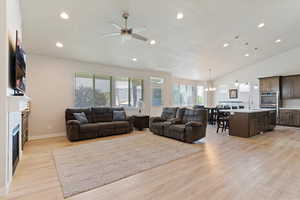 Living room with ceiling fan, light wood finished floors, recessed lighting, a fireplace, and a chandelier
