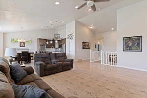 Living area featuring light wood-style floors, a chandelier, a ceiling fan, recessed lighting, and high vaulted ceiling