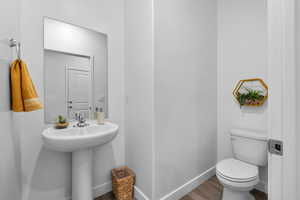 Half bath featuring toilet and wood finished floors