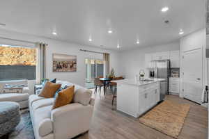 Kitchen with open floor plan, appliances with stainless steel finishes, white cabinets, recessed lighting, and wood finished floors