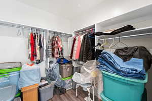 Spacious primary bedroom walk in closet featuring wood finished floors