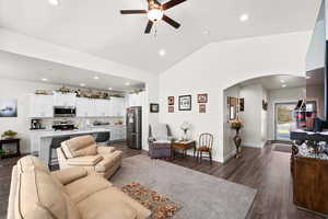 Family room featuring arched walkways, a ceiling fan, lofted ceiling, dark wood-type flooring, and recessed lighting