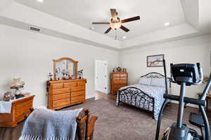Primary bedroom featuring recessed lighting, a raised ceiling, ceiling fan, and carpet flooring