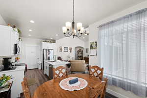 Dining room featuring dark wood-type flooring, arched walkways, recessed lighting, and a chandelier