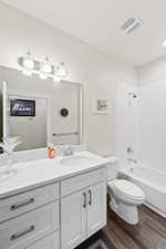 Full bath featuring wood finished floors, vanity, and tub / shower combination