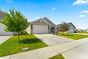 View of front of house featuring a front lawn, driveway, an attached garage.
