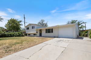 Tri-level home with brick siding, a garage, and concrete driveway