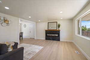 Living room featuring light wood-style flooring, recessed lighting, and a premium fireplace