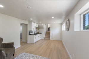 Living area featuring light wood-style flooring, a textured ceiling, recessed lighting, and stairway