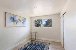 Unfurnished bedroom with light wood-style floors, a textured ceiling, and a closet