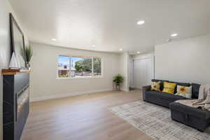 Living area with a fireplace, light wood-style flooring, and recessed lighting